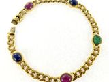 a close up of a gold bracelet with multi colored stones