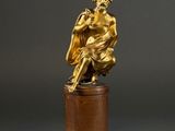 an image of a gold statue of a man sitting on top of a wooden pedestal