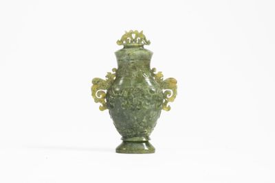 un vase vert posé sur une surface blanche