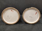 two white and brown plates with red designs on them