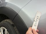 a person holding a measuring tape to measure a car ' s tire