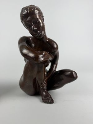 sculpture of a woman sitting on the ground with her hands on her knees