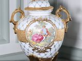 un vase blanc orné d'un motif doré, posé sur une table