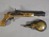 un vieux pistolet et une cloche en laiton posés sur une surface blanche