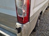 the rear end of a silver van parked on gravel in a parking lot