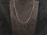 un collier posé sur un présentoir pour mannequin, sur fond noir