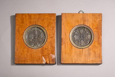 two wooden plaques with a silver medallion on them hanging on a wall