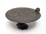 a silver plate with a snail on it on a stand