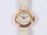 a gold watch with a white face on a white surface