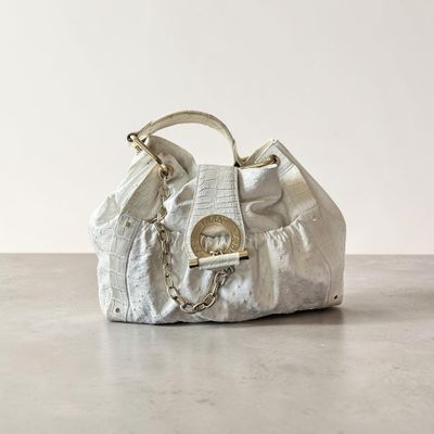 un sac à main blanc posé sur une table près d'un mur blanc