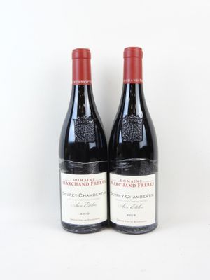 deux bouteilles de vin rouge posées l'une à côté de l'autre sur une surface blanche