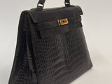 a black crocodile skin handbag with gold hardware on the handle