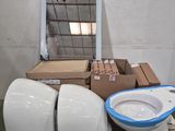 des toilettes blanches posées sur une palette, à côté de toilettes bleues et blanches