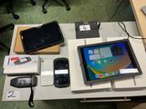 une tablette posée sur une table, à côté d'autres appareils électroniques