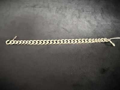 a silver chain bracelet on a black surface