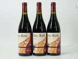 three bottles of red wine sitting on top of a white table