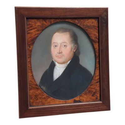 portrait d'un homme vêtu d'un manteau noir et d'une chemise blanche, dans un cadre en bois