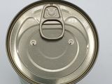 an open can of food with a metal lid on a white surface