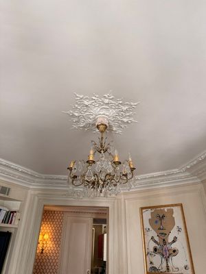 a chandelier in the middle of a room with paintings on the walls