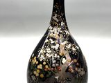 un vase noir orné de fleurs, posé sur une table