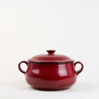 le grand pot rouge est posé sur une surface blanche