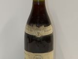 une vieille bouteille de vin posée sur une table blanche