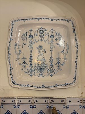 une assiette bleue et blanche accrochée au mur au-dessus d'un évier
