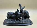 sculpture représentant trois lapins sur un rocher au bord d'un ruisseau