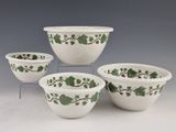 four white bowls with green ivy designs on them sitting on a table
