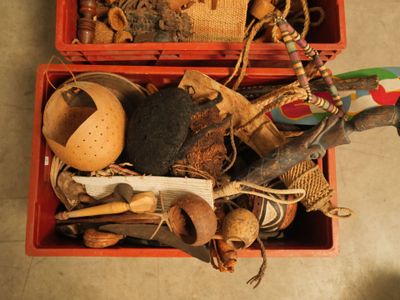 une boîte rouge remplie d'objets divers, posée par terre