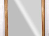 un grand miroir à cadre doré posé sur un mur de briques blanches