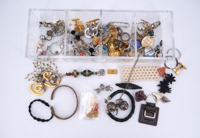 an assortment of assorted jewelry in a clear box on a white surface