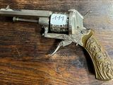 un vieux revolver posé sur une table en bois, avec une étiquette dessus
