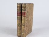 two old books sitting on top of each other on a white surface