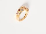 an image of a gold ring with multi colored stones on a white surface