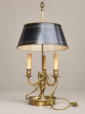 une lampe de table en laiton avec un abat-jour noir et deux bougies