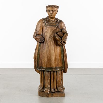 a wooden statue of a man holding a book in his hands