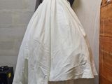 a white dress hanging on a clothes rack in a room