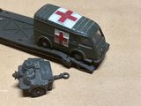 un camion miniature orné d'une croix rouge, à côté d'un char miniature