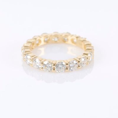 a yellow gold ring with white diamonds on a white background