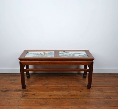 une photo d'une table basse avec un plateau en verre posée sur un parquet