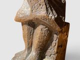 une photo représentant une sculpture d'un homme assis sur un rocher
