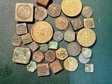 quelques vieilles pièces posées sur une table, à côté d'une pile de pièces plus petites