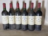 six bottles of wine are lined up in a row on a table