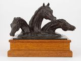 sculpture représentant trois chevaux sur un socle en bois, sur fond blanc