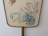 two birds flying in the sky above a hand painted fan