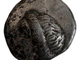 une pièce de monnaie ancienne représentant un squelette sur fond blanc
