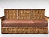 une photo d'un canapé en osier avec un coussin en cuir marron
