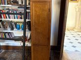 a tall wooden cabinet in front of a bookshelf