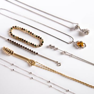 various types of necklaces and bracelets laid out on a white surface